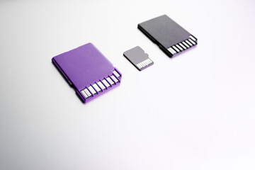 purple and black memory cards on white surface, selective focus. black flash memory card on wood texture concept.