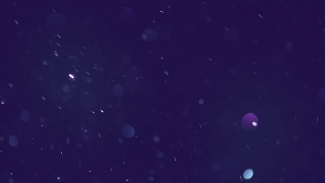 Abstract particles floating, motion, random flickering. Colorful Dust sparkles on dark background. Real Glittering sparkling particles Bokeh. Holiday backdrop. Slow motion 4K UHD video