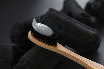 Bamboo toothbrush with charcoal bristles and toothpaste on the charcoal pieces