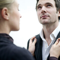 Businesswoman adjusting businessman's suit