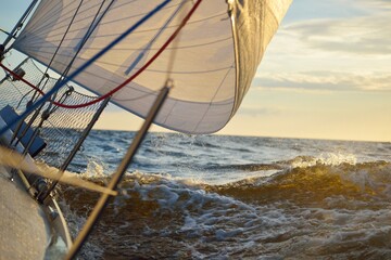 White sailboat in an open sea at sunset. Single handed sailing a 34 ft yacht. Close-up view of the...