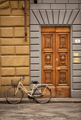 Fototapeta na wymiar Bicycle parked on the kerb in front of an ornate timber door in Florence