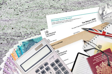 English form sa100 Tax return by HM revenue and customs lies on table with office items. HMRC...