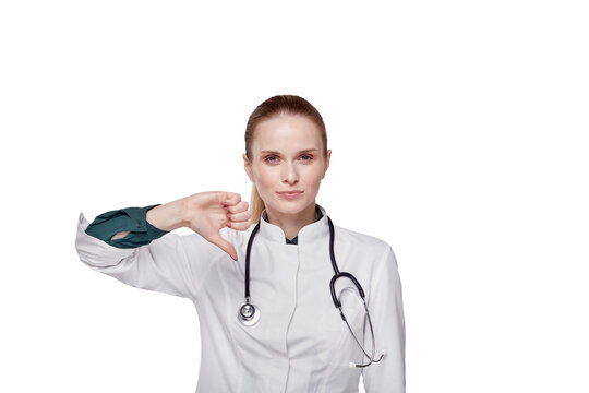 Beautiful woman in a medical coat shows thumb down gesture. Isolated background.