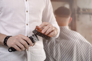 Obraz na płótnie Canvas Barber cleaning electric hair clipper at barber shop.