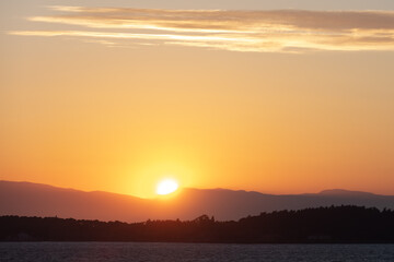 Dramatic sunrise landscape at Urla, Izmir, Turkey. Beautiful blazing sunrise landscape over bright blue sea and orange cloudy sky