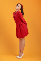 Beautiful lovely girl in red dress isolated on orange background in full body.