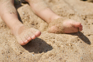 Feet of a child in the sand on the beach. The concept of carelessness and relaxation.