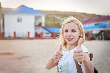 Positive woman smiles and holds thumbs up on vacation.