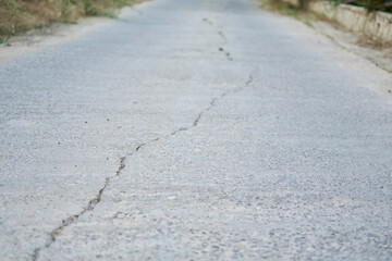 road going into the distance with a crack in the asphalt.