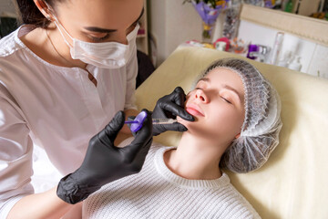 Cosmetologist doctor do injection procedure to a woman in her clinic. She wear black glowes and...
