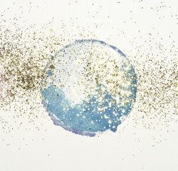 Golden glitter on abstract round blue watercolor splash on light gray background	