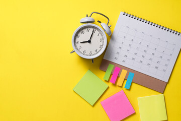 close up of calendar and alarm clock on the yellow table background, planning for business meeting or travel planning concept