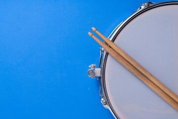 Drum stick and drum on blue table background, top view, music concept