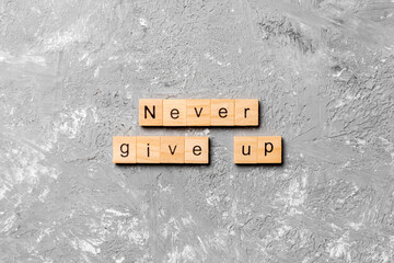 never give up word written on wood block. never give up text on cement table for your desing, concept