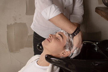 Young man having his hair washed in a hairdressing salon before or after hair cutting.