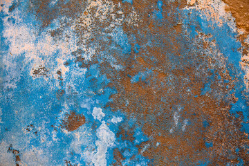 Blue texture wall with broken plaster. Details of damaged wall with pealing paint due to wall damp and mold. 