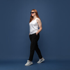 Confident in eyewear. Young woman in casual wear on blue studio background. Bodypositive character, feminism, loving herself, beauty concept. Plus size girl looks happy, confident. Inclusion