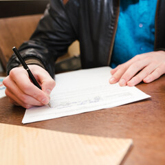 A man fills out a document form. Hands close-up