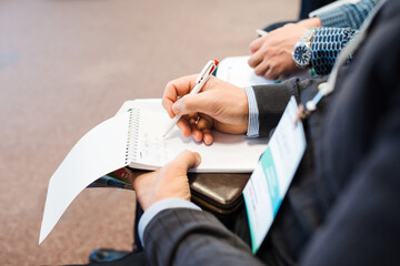 Businessman makes notes at a business seminar. Close up businessman hand holds a pen and writes. businessman doing paperwork