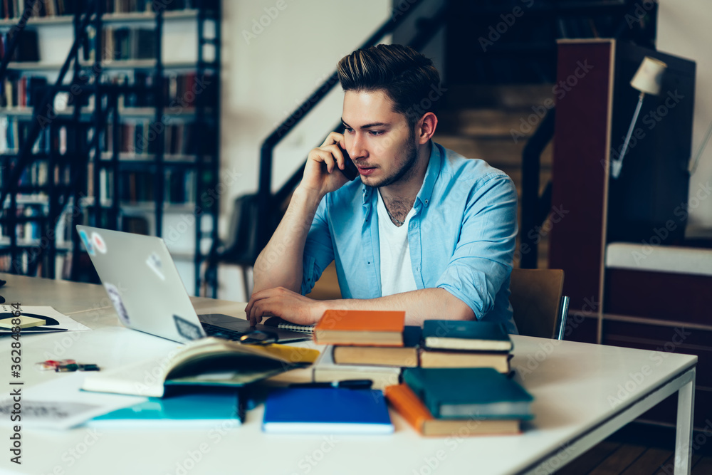 Aufkleber pensive male freelancer making telephone call while working online on laptop computer, serious man l