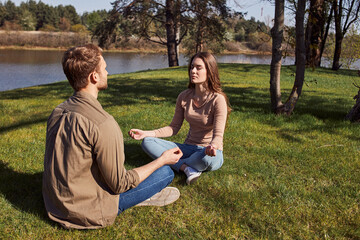 Happy young couple meditating with eyes closed outdoors