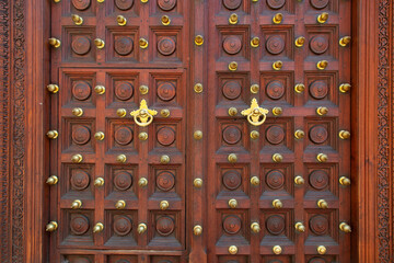 Details of Khoja Ismailia mosque door in Zanzibar with brass knobs and knocker. 