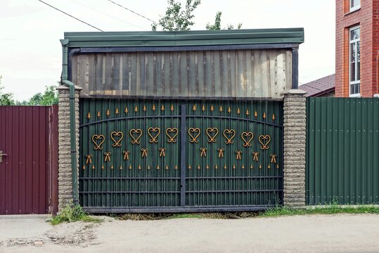iron green gate with forged pattern and part of the metal fence on the street