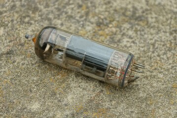 one old glass transistor lamp lies on a gray stone in the street