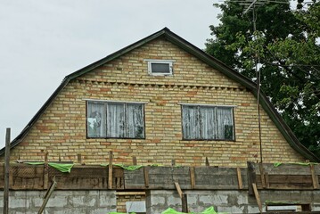 brown brick loft of an old private house with two windows against a gray sky