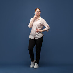 Talking phone. Young woman in casual wear on blue studio background. Bodypositive character,...