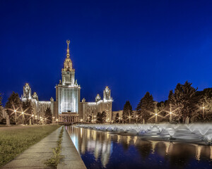 Fototapeta na wymiar The complex of fountains in front of the main building of Moscow State University at blue hour. Beautiful illumination of a monumental building of the Soviet era on the Sparrow Hills in Moscow. 