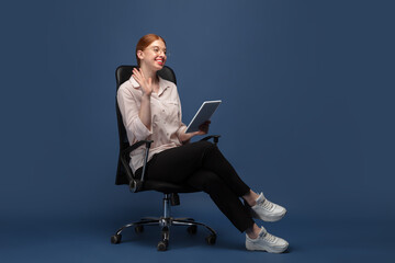 Happy worker with tablet. Young woman in casual wear on blue background. Bodypositive character,...