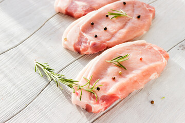 Raw pork fillet and rosemary on a white board top view.