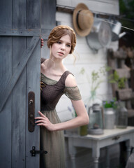 Art photo of a gentle girl with braided hair outside the barn door
