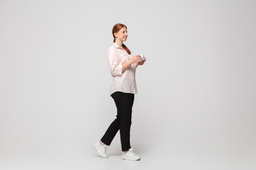 Fototapeta na wymiar Coffee time. Young woman in casual wear on white background. Bodypositive character, feminism, loving herself, beauty concept. Plus size businesswoman during paperwork. Inclusion, diversity.