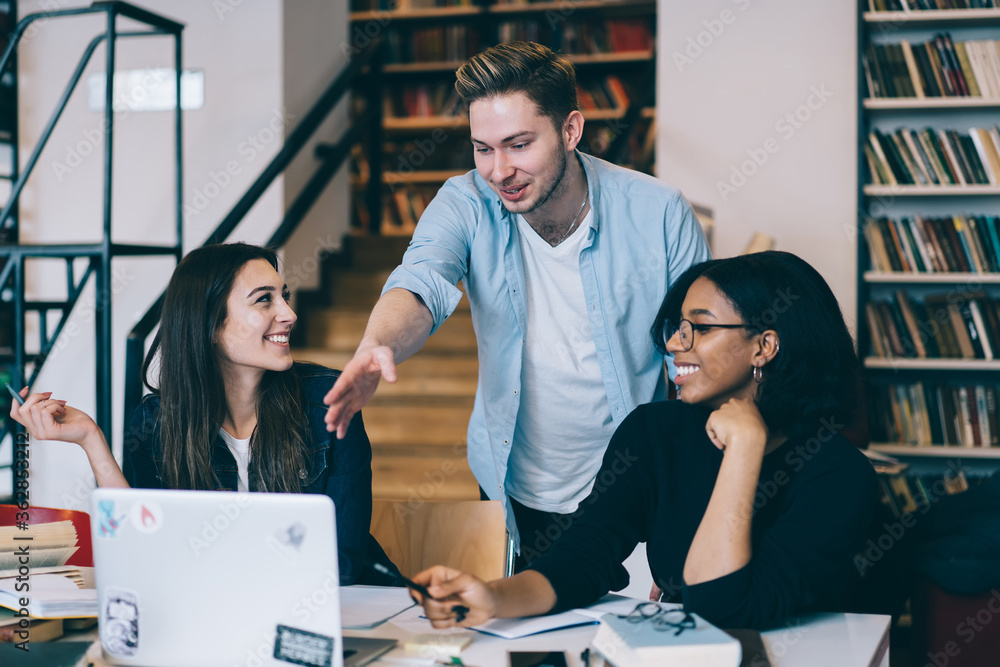Poster positive hipster guy pointing on laptop computer while watching webinar for education with diversity