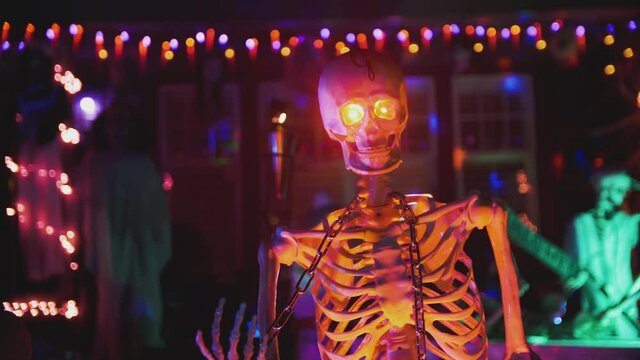 Spooky skeleton halloween garden decoration in the dark at night with red eyes - scary halloween house - 4k slow motion video