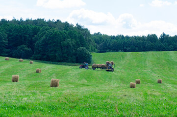 A tractor in an agricultural field harvests hay