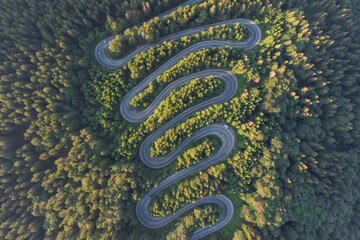 Aerial view of beautiful mountain road crossing a green forest
