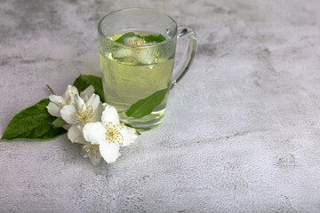 Obraz na płótnie Canvas Freshly brewed tea with mint and a jasmine flower on a light background.