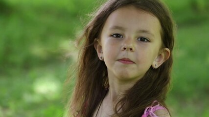 Little girl turns and looks at the camera, then covers her face with her hands and makes faces