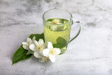 Fototapeta na wymiar Freshly brewed tea with mint and a jasmine flower on a light background.