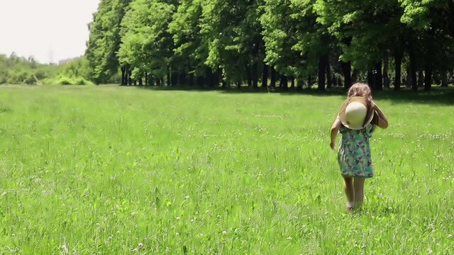 Little girl walks on a green lawn and watches the flight of soap bubbles