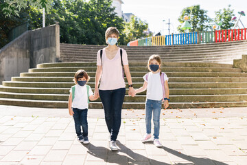 Mother with two children going to school at the beginning of the year with masks on their faces