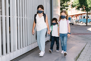three brothers entering school at the beginning of the year with masks on their faces