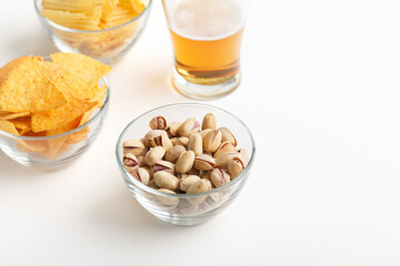 Crunchy snacks for beer. Nachos, pistachios and chips in glass plates and light ale in glass