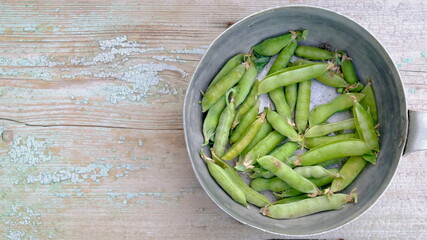 Peapods in aluminium cup on the wood with copyspace