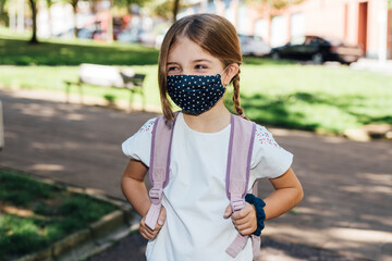 Blonde girl going to school at the beginning of the year with masks on her face