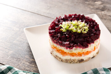 Traditional Russian herring salad with beetroot and carrots on wooden table	